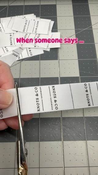 Person cutting Sew In Seam Tags Labels for Scrunchies Wristlets Blankets Crafts at a crafting table